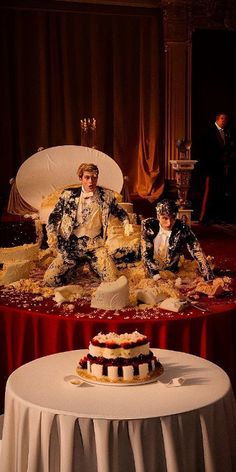 two cakes sitting on top of a white table covered in red and gold cloths