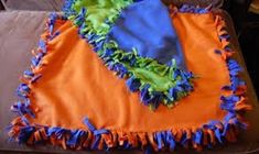 an orange and blue blanket with ruffles on it sitting on top of a couch