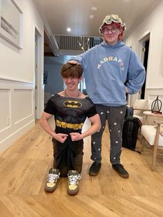 a man standing next to a boy in a batman costume