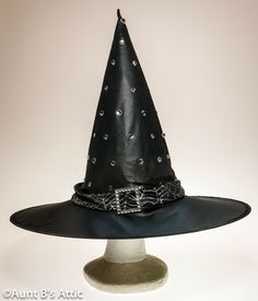 Dressy jeweled witch hat, is in a black poly, that has almost a satin shine to it. Trimmed with a silver spider web design band, and accented with a rhinestone buckle. Includes an extra pack of jewels. 5" wired brim, 14 1/2" crown. Very pretty!