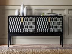 a black and white cabinet with two vases on top of it next to a wall