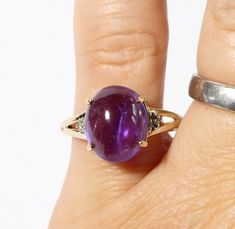 Here is a 9ct gold natural Amethyst ring with Diamonds.  The oval cabachon Amethyst is claw set into a basket mount and flanked either side with 3 tiny Diamonds, all in solid yellow gold. The Amethyst is a natural stone in a lovely medium colour of purple with natural striations within.  It's a gorgeous stone! Hallmarked to the inner shank for Birmingham England 9ct gold 375 and the makers mark is CR.   It is a UK size approx N. 1/2 and a US size approx 7.   The Amethyst measures approx 11.5mm x Oval Cabochon Amethyst Ring For Formal Events, Oval Cabochon Amethyst Ring For Formal Occasions, Anniversary Yellow Gold Amethyst Cabochon Ring, Gold Amethyst Oval Cabochon Ring, Oval Amethyst Ring With Accent Stones, Heirloom Cabochon Amethyst Ring For Anniversary, Yellow Gold Cabochon Amethyst Ring Gift, Oval Amethyst Ring With Accent Stones For Anniversary, Oval Cabochon Gemstone With Polished Finish For Anniversary