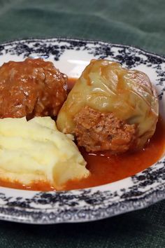 meatballs, mashed potatoes and gravy on a black and white plate