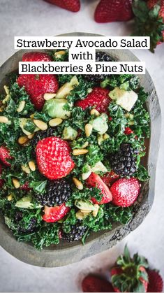 a wooden bowl filled with mixed berries and greens