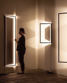 a woman is standing in front of two mirrors with light coming through the holes on them