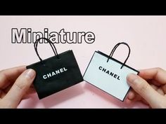 two hands holding small black and white bags with the words miniatureture on them,