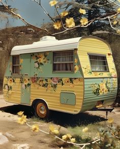 an old camper with flowers painted on it's side parked in the dirt