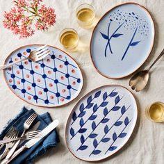 three plates with designs on them sitting on a table next to utensils and silverware