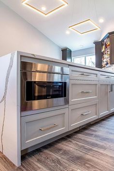 a large kitchen with stainless steel appliances and white cabinetry, along with hardwood flooring