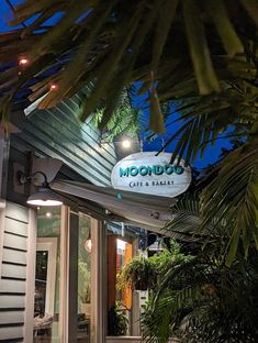 the moondog cafe and bakery is lit up at night with palm trees surrounding it