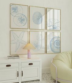 a living room with four framed pictures on the wall and a white chair next to it