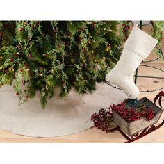 a christmas tree skirt with stockings on it next to an old book and holly wreath