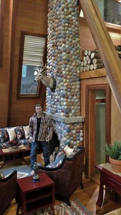 a man standing in front of a living room filled with furniture and rocks on the wall