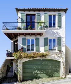 a two story house with green shutters and balconies on the second floor