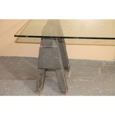 a glass and metal table sitting on top of a cement floor