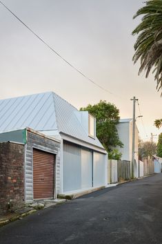 an empty street with two garages and palm trees on the side of the road