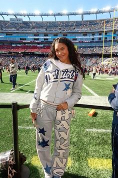 a woman standing on top of a football field wearing star print sweatpants and sneakers