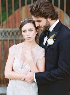 a bride and groom standing next to each other in front of an iron gate at their wedding