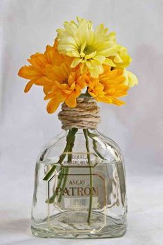 yellow and orange flowers are in a clear glass bottle with twine around the top