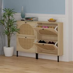 a wooden cabinet with baskets and shoes on it next to a potted palm tree