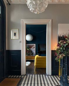 the hallway is decorated with black and white checkered flooring, chandelier, and yellow chair