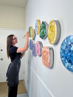 a woman is painting on the wall with different colors