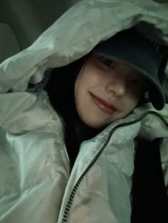 a woman in a white jacket and black hat with a hood up on her head