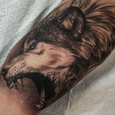 a man's arm with a tattoo of a wolf and his mouth is open