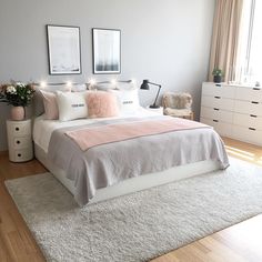 a bedroom with white and pink bedding, pictures on the wall and rugs