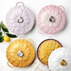 four flower shaped dishes on a white surface with lemons and leaves in the background