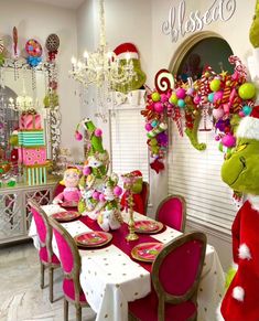 a dining room decorated for christmas with pink and green decorations on the table, grino's hat hanging from the ceiling