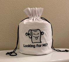 a white bag sitting on top of a toilet with the words looking for me?