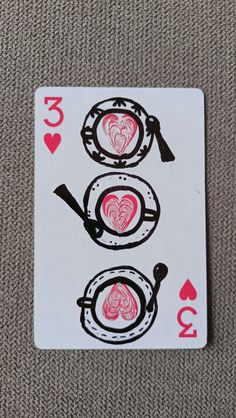 a playing card with three hearts in the middle and two on each side, sitting on a carpeted surface