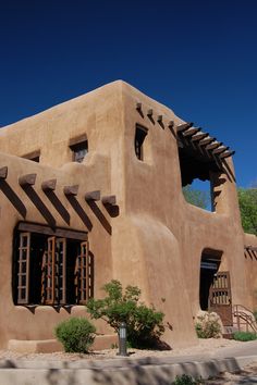 an adobe - style building with wooden windows and shutters