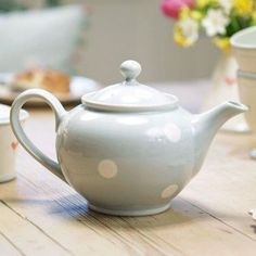 a polka dot tea pot sitting on top of a wooden table