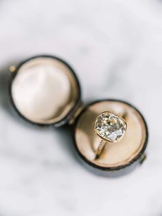 an engagement ring with a diamond in it on a white marble surface, photographed from above