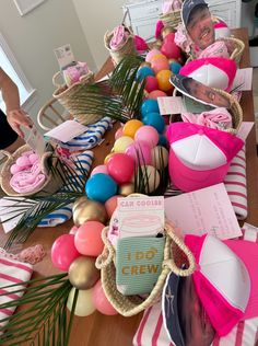 a table topped with lots of pink and blue items next to palm leaves on top of it