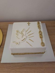 a white cake with gold decorations and a dove on it