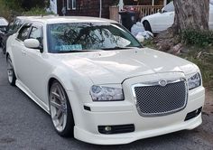 a white car parked in front of a tree