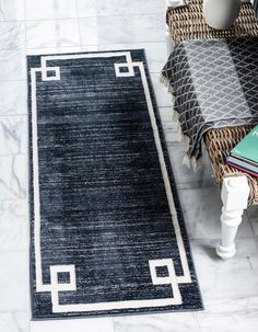 a black and white rug on the floor next to a wicker chair with a book