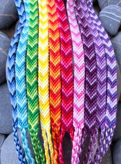 several braided bracelets with different colors and patterns on top of some gray rocks