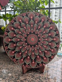 an intricately designed wooden plate sitting on top of a counter next to a potted plant