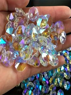 a hand is holding several different colored diamonds in it's palm, and there are many smaller ones on the other side