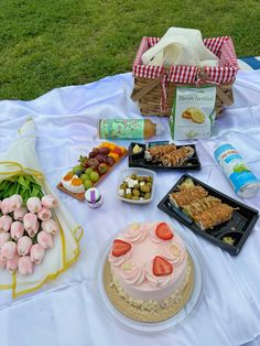 a picnic table with food and snacks on it, including cake, crackers, grapes, strawberries