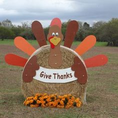 a large hay bale sign with a turkey on it that says give thanks in front of an open field