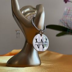 a close up of a keychain on a table with a vase in the background