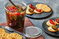 two plates with crackers and pickles on them next to a jar of pickles