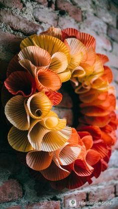 an orange and yellow wreath on a brick wall