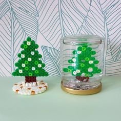 a glass jar filled with beads next to a small green christmas tree on top of a table