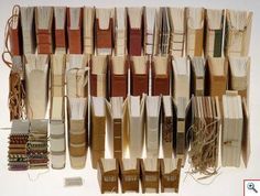 many books are stacked on top of each other with strings attached to them, all in different colors and sizes